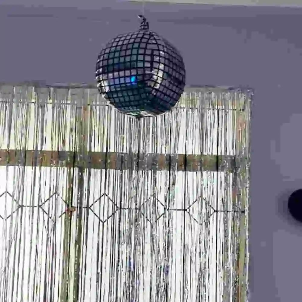 Disco theme birthday decor with disco ball and curtain backdrop