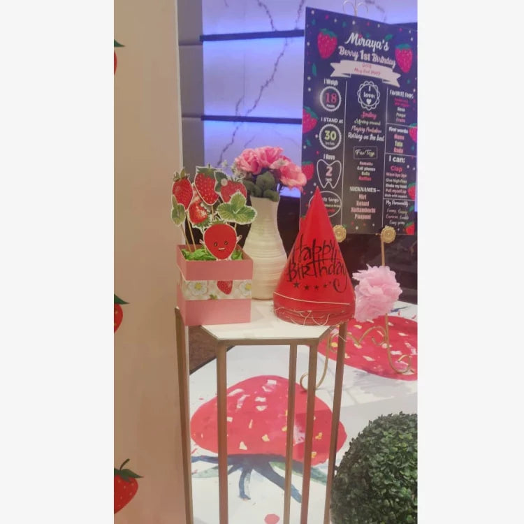 Get Berry First Birthday Decor with strawberry-themed table props, floral arrangement and birthday accessories