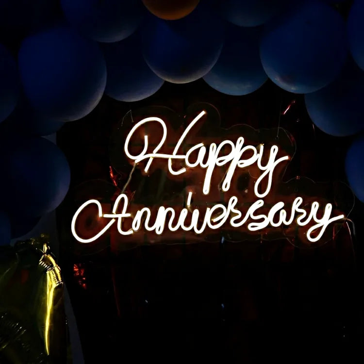 Blue anniversary balloon backdrop with illuminated Happy Anniversary neon sign
