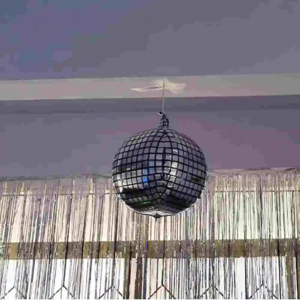 Get disco theme birthday decor with a hanging disco ball and fringe backdrop