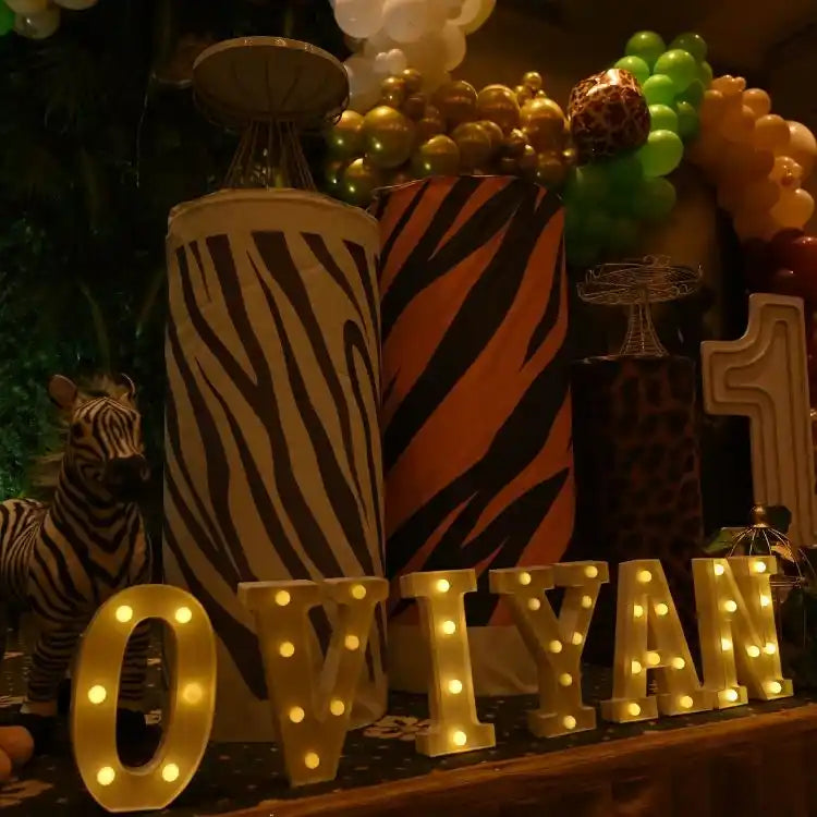 Order jungle safari birthday decor package with animal-themed cake table and illuminated number decor