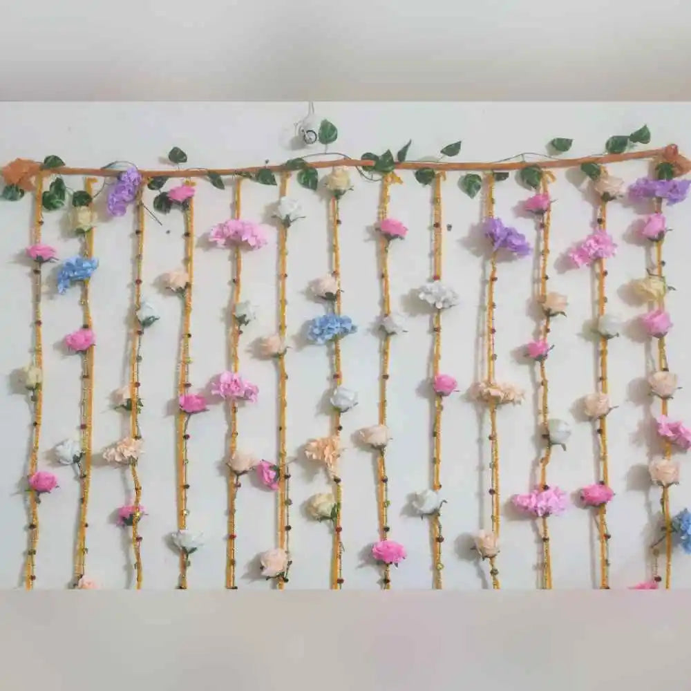 Order Wedding Floral Decor at Home with hanging flower strings, green foliage and colourful floral wall decoration